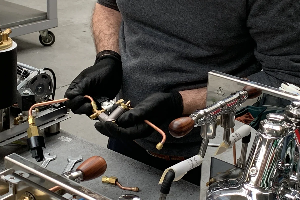 Un artisan assemble des composants en cuivre et en laiton dans une machine à espresso Bezzera à l’usine.